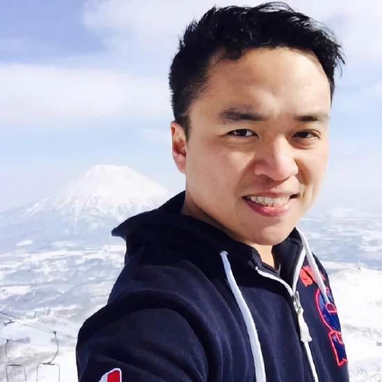 Shawn (Swyx) Wang at the top of a ski lift with A snow-coloured volcano in the background.